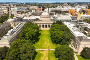 A drone shot of people gathering on a pathway in front of MIT's "Great Dome" building.