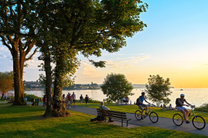 A group of people riding bicycles on a path near the lake.