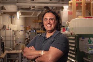 Amos Winter stands with hands folded, smiling, in a lab