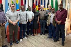 A group of 9 people posing in front of various country flags