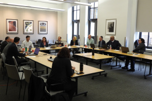 A large group of people sitting around tables put together in the shape of a "U" at a workshop