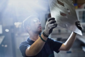 Peter Godart looks at a large sheet of metal he is holding up to the light