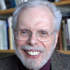 White man with gray hair and beard, smiling broadly and wearing glasses