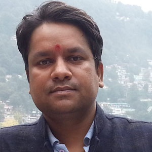 Indian man with short black hair city and hill in background