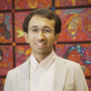Arjav Shah standing in front of a colorful mural