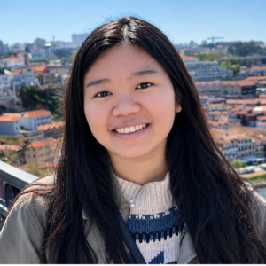 Hao Nghi Luu stands outside above what looks like a European city along a river 