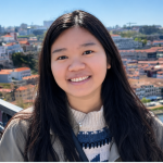 Hao Nghi Luu stands outside above what looks like a European city along a river 