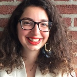 woman smiling with glasses, curly hair, and red lipstick