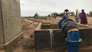 Large water pipe with African women walking in background