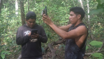 Two researchers in Amazon mapping archaeological features with GPS and tablet