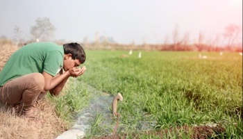 Man drinking from water from pipe in ground