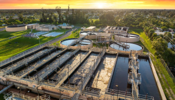 Water treatment facility with multiple tanks and filtration units shown from an aerial shot above with a setting sun in the background