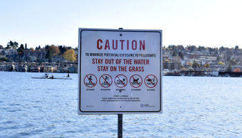 Caution sign that says "To minimize potential exposure to pollutants, stay out of the water stay on the grass"