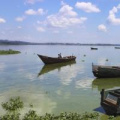 An image of a a boat floating on a calm reflective Lake Victoria. 