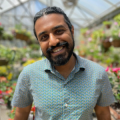 Gokul Sampath standing in a greenhouse with plants behind him
