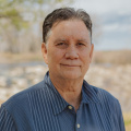 Dana Hoag stands outside above a valley in a blue button down shirt